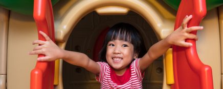 Asian Chinese little girl playing in toy house at indoor playground.