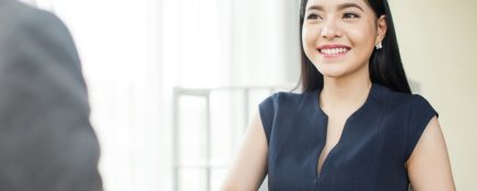 Beautiful Asian businesswoman smiling and shaking hands with other businessman