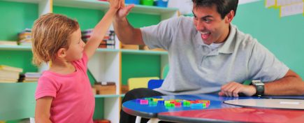 Preschool teacher and child giving a high-five in classroom