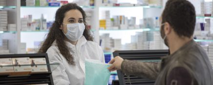 Female pharmacist wearing a surgical mask gives medication to the patient